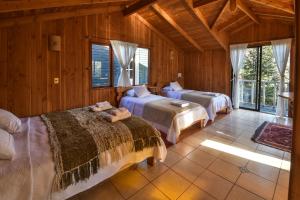 two beds in a room with wooden walls and windows at Hola Pucon in Pucón +30 photos