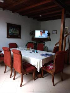 a dining room table with red chairs and a television at Hostal Famihotel Fundadores in Jardin