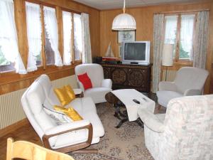 ein Wohnzimmer mit weißen Stühlen und einem TV in der Unterkunft Chalet Kanderhus in Kandersteg