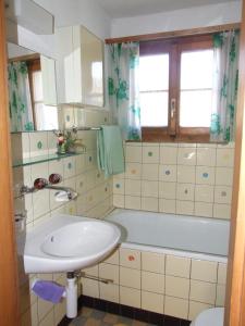 La salle de bains est pourvue d'un lavabo et d'une baignoire. dans l'établissement Chalet Kanderhus, à Kandersteg