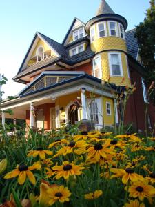 una casa gialla con una torre in cima a un campo di fiori di A Moment in Time Bed and Breakfast a Niagara Falls