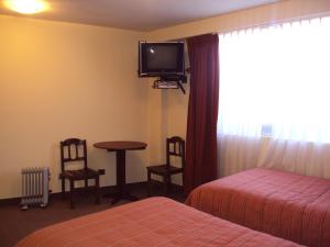 a hotel room with a bed and a table and a tv at Mosoq Inn in Puno