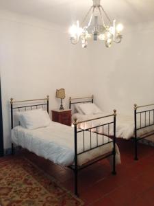 two beds in a bedroom with a chandelier at Casa da Lagoa Guest House in Évora