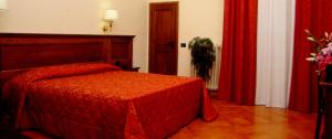 sypialnia z czerwonym łóżkiem i czerwonymi zasłonami w obiekcie Hotel California we Florencji