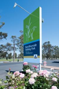 a sign for a holiday park with pink flowers at Berri Riverside Holiday Park in Berri