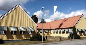 een geel gebouw met een rood dak en een witte vlag bij Hotell Hässlö in Västerås