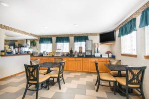 a kitchen with wooden tables and chairs and a counter at Days Inn & Suites by Wyndham Wichita in Wichita