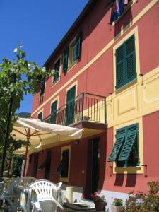 a pink building with a balcony and an umbrella and chairs at Affittacamere Cerisola 2003 in Zoagli