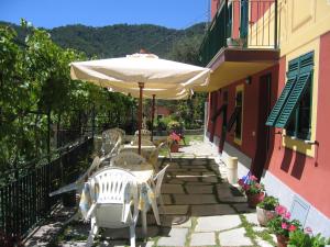 een patio met een tafel en stoelen en een parasol bij Affittacamere Cerisola 2003 in Zoagli