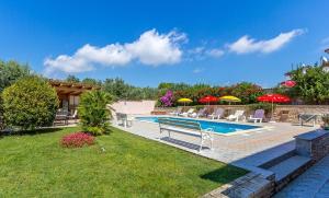 a swimming pool with chairs and umbrellas in a yard at Apartments Winny in Banjole