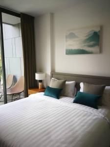 a bedroom with a large white bed with blue pillows at The Valley Khao Yai-2 Bed Room in Ban Huai Sok Noi