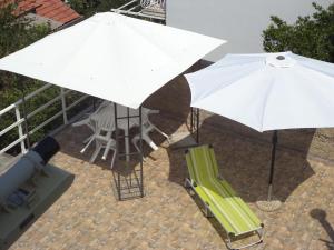 a white umbrella and a green chair and a table with at Apartments & Rooms Abba in Dubrovnik
