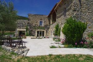 - un bâtiment en pierre avec une terrasse en face dans l'établissement Chambres d'Hotes La Grange au Negre, à Alba La Romaine