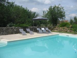 a swimming pool with lounge chairs and an umbrella at Gite Le Village in Normier