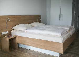 1 cama con sábanas blancas y cabecero de madera en Haus NordQuartier, en Norderney