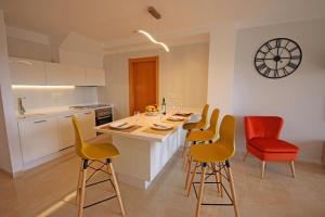 a kitchen with a table with chairs and a clock on the wall at LA PERLA by RENTMEDANO superb luxury duplex, private roof terrace, ocean view, pool, WiFi and parking in El Médano