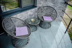 un patio con 3 sillas y una mesa con cojines morados en City Lux Villa, en Bucarest