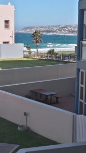 a picnic table on the balcony of a building with the beach at La Palma Villas in Mossel Bay