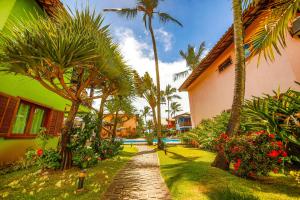 un chemin en briques devant une maison plantée de palmiers dans l'établissement Residence Pé na Areia, à Arraial d'Ajuda