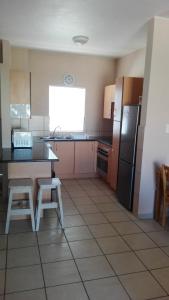 a kitchen with a table and a refrigerator at La Palma Villas in Mossel Bay