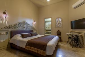 a bedroom with a large bed and a flat screen tv at Maison d'Hôtes Dar Ennassim in La Marsa