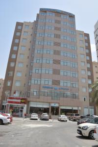 a large building with cars parked in a parking lot at Continental Inn Hotel Al Farwaniya in Kuwait