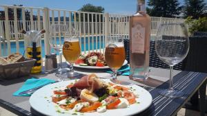 uma mesa com dois pratos de comida e copos de vinho em Hotel de la Poste em Peymeinade