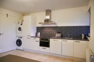 a kitchen with white cabinets and a washer and dryer at Harlingen Garden Apartment in Midlum