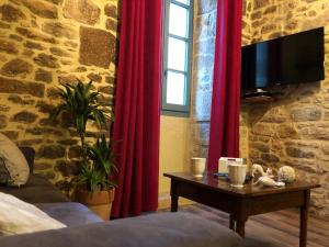 - une chambre avec des rideaux rouges et une table avec une télévision dans l'établissement Maison de Charme dans la Cité, à Sarlat-la-Canéda