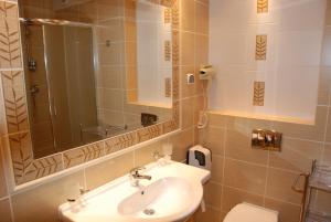 W łazience znajduje się umywalka, lustro i toaleta. w obiekcie Panoramic-Oscar w mieście Mrągowo