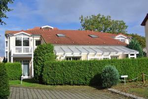 a white house with a red roof and a hedge at Ferienwohnungen am Rosenhof in Kühlungsborn