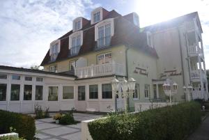 a large white building with a brown roof at Ferienwohnungen am Rosenhof in Kühlungsborn +17 photos
