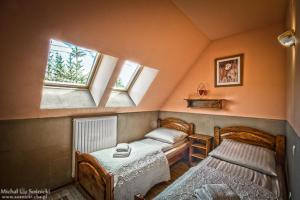 two beds in a room with two windows at Pensjonat Szczebel in Mszana Dolna