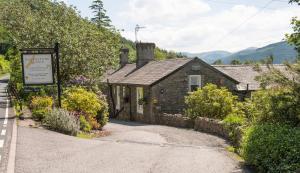 uma casa de pedra com um sinal em frente em Ravenstone Lodge Country House Hotel em Keswick