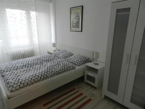 a white bedroom with a bed and a window at Apartman Perica in Zagreb