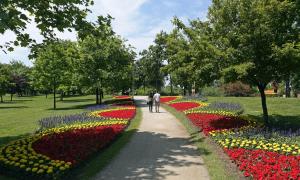 a man walking down a path in a park with flowers at Apartman Perica in Zagreb