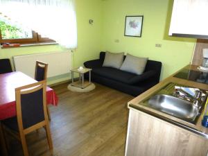 a kitchen and a living room with a couch and a sink at Abseits vom Lärm und Verkehr in Litzendorf