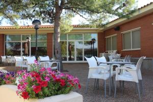 un patio con tavoli, sedie bianche e fiori di Camping Fayón Fishing a Fayón