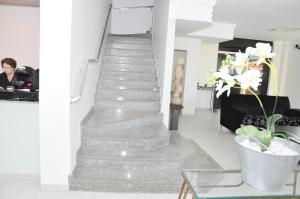 a staircase in a living room with a vase of flowers at Delta Hotel Rondonopolis in Rondonópolis