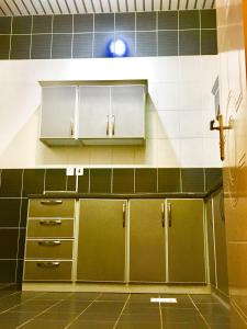 a kitchen with green and white tiled walls and cabinets at Najmat Sabbabah Furnished Units in Hail +41 photos