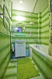 baño de azulejos verdes con bañera y lavamanos en Lakshmi Rooms Park Pobedy, en Moscú