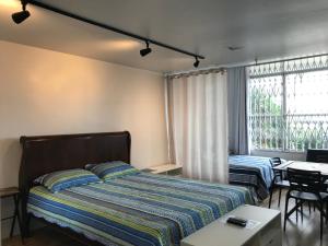 1 dormitorio con cama, mesa y ventana en Atlantica Lofts, en Río de Janeiro