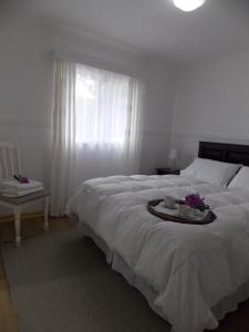 een slaapkamer met een groot wit bed en een dienblad met bloemen erop bij Cabañas Inadeqin in La Ensenada