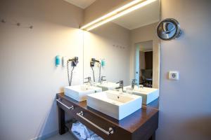 a bathroom with three sinks and a large mirror at Retro Design Hotel in Langeoog