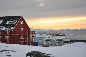 a red house in a small town in the snow at HOTEL SØMA Ilulissat in Ilulissat