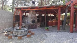 a patio with a stone fireplace and a wooden pavilion at Juniperus Park Hotel Kecskemét in Kecskemét