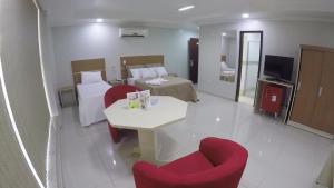 a hotel room with a bed and a table and chairs at Hotel Coimbra in Tucuruí
