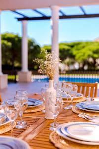 a wooden table with glasses and a vase with flowers at Casa da Praia Verde in Praia Verde