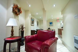 a waiting room with a red leather chair and a table at Hotel Bon Accueil in Montréal