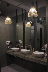 a row of four sinks in a bathroom with mirrors at Ekanek Hostel in Bangkok